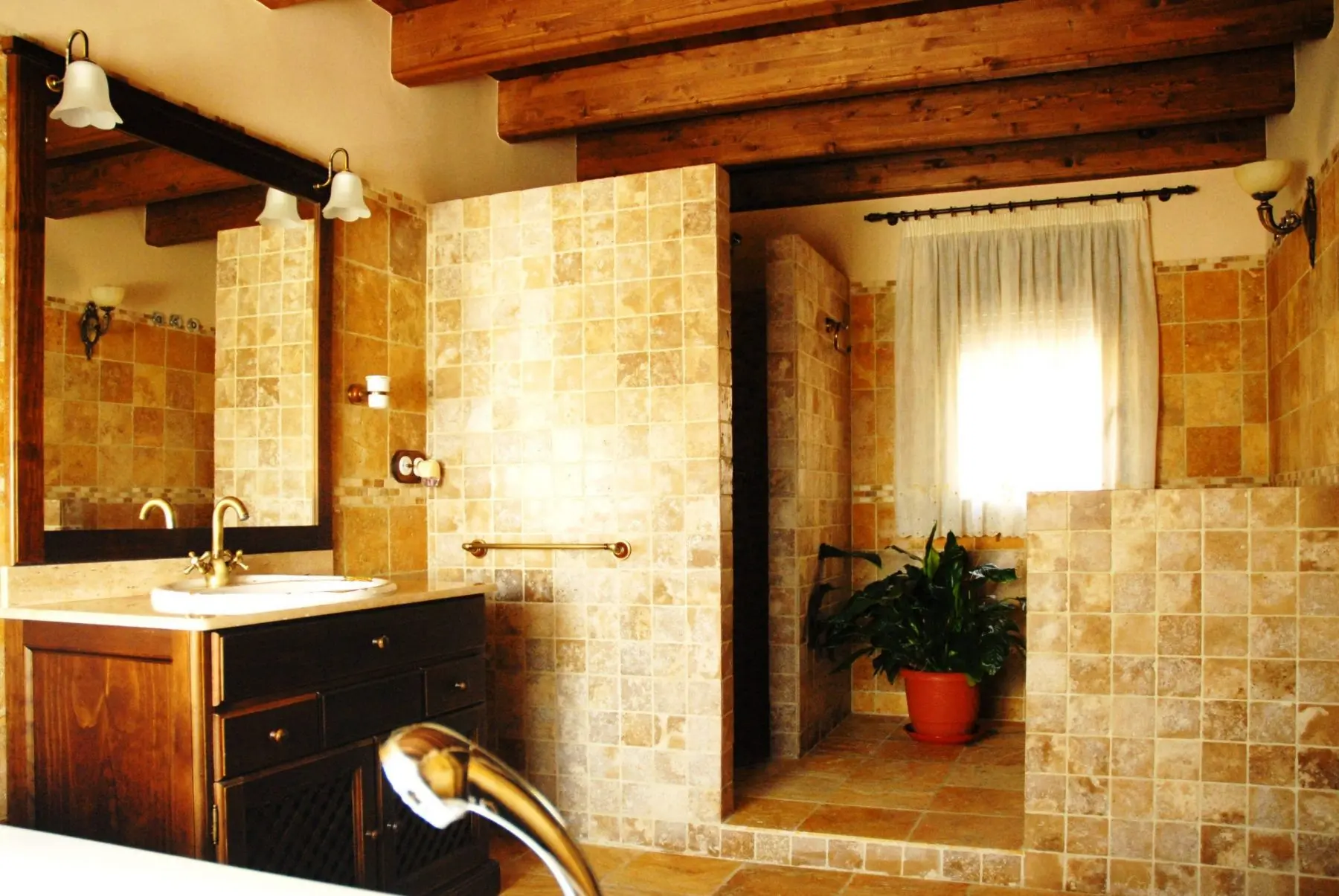 Baño con lavabo de madera, ducha y vigas vistas de Mas d’Albalat