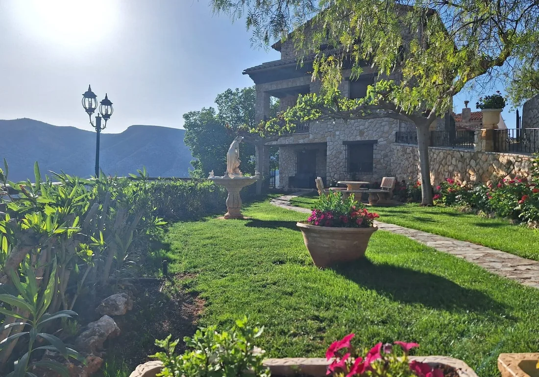 Fachada de piedra y jardín de Mas d’Albalat con vistas a las montañas