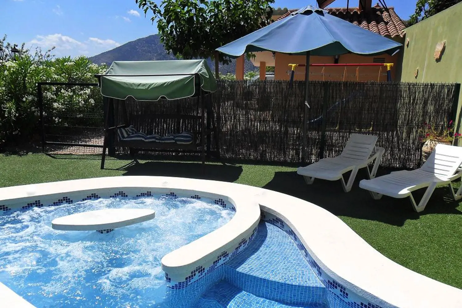 Jacuzzi integrado en la piscina privada de Mas d’Albalat, junto a las tumbonas y el jardín